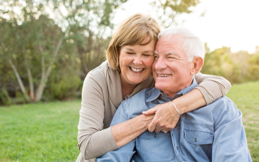 Elderly couple hugging and smiling in a park
