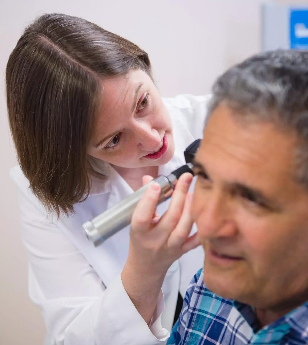 Earwax removal doctor inspecting a male patient ear
